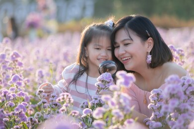 cute asian child girl and her mother enjoying with beautiful flower together and little girl holding magnifier looking on flower with fun and curiously in the flower garden.