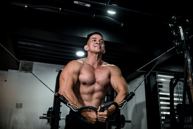 a handsome and athletic asian man does some cable crossovers. chest day workout training at the gym.