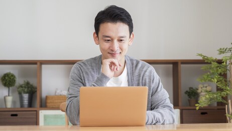 asian man using a computer in the living room
