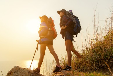 group asia young women of hikers walking with backpack on a mountain at sunset. traveler going camping. people travel and adventure leisure and destination in holiday.  travel concept