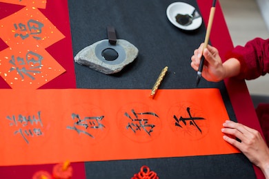 close up of writing spring festival couplets to celebrate chinese holidays with word meaning happy new year 