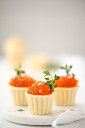 red salted salmon caviar in tartlets decorated with thyme sprigs, close-up