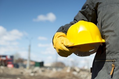 builder with yellow hardhat and gloves, selective focus