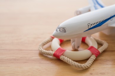 travel insurance business concept. airplane or plane on lifebuoy with wooden background copyspace. travel insurance covers loss suitcase, flight delays, cancellations, evacuations and medical expenses