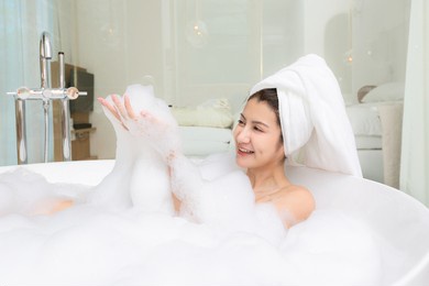 happy asian woman bathes with white foam in a bathtub fun emotions.