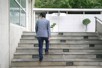 businessman going up staircase. rear view. urban setting.