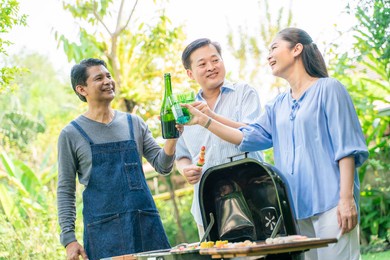 group of asian friends camping and having a barbecue in home garden dinner time