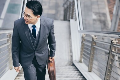 happy businessman going to his office for work in morning by walking on steps of overpass with happy and smile face handsome man wear suit, necktie and holding briefcase business and finance concept