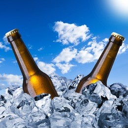 cold beer bottles on ice cube with blue sky background