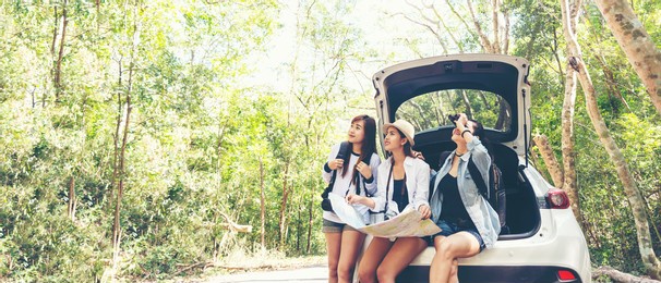 travel group asian woman traveler sitting on hatchback car for trip adventure road with outdoors forest in vacations and holiday trips. travel concept, copy space for banner