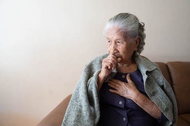 asian senior ill female have a cough and sore throat. causes of cough include common cold, flu, respiratory tract infection, pneumonia, bronchitis, allergy or asthma. elderly health care concept.