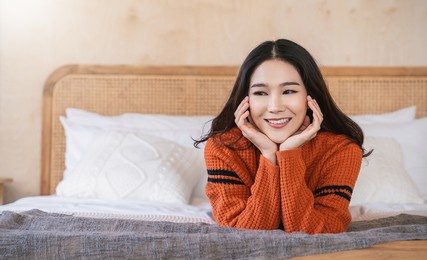 portrait of young beautiful asian woman relax bedroom. smile happy asian girl hands cover face wear winter cloth. beauty treatment perfect clear skin japanese woman makeup winter hygge concept banner