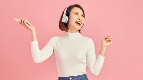 favorite song. happy asian girl listening to music on mobile phone with headphones. free space