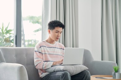 happy young man uses his laptop to check email and check work online. working at home concept.