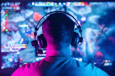 professional cyber gamer studio room with personal computer for stream in neon color blur background. back view soft focus.