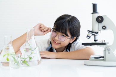 happy asian girl scientists learning and doing analysis for germs with glassware and microscope in the laboratory. educational. early development of children. research and development concept