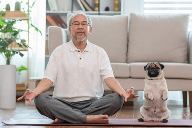 asian elderly senoir man doing yoga with dog pug breed in living room at home,happy retired at home concept 