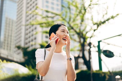 young adult asian business single woman using mobile phone talking with friend. happy face and laugh. city lifestyle working people. backgroud at outdside on day.