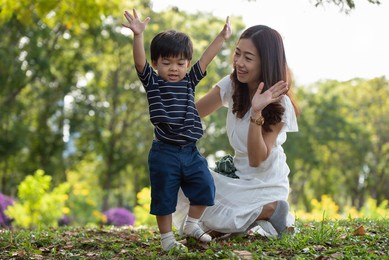 happy asian family having fun mother and her son playing in the park together