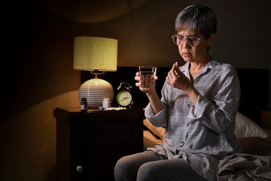 asian senior woman taking medicine at bed room