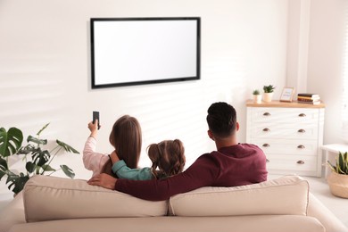family watching tv on sofa at home, back view