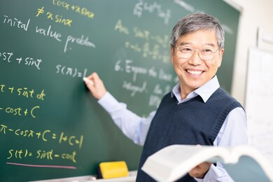 asian senior male calculus professor is writing on blackboard in the classroom at college