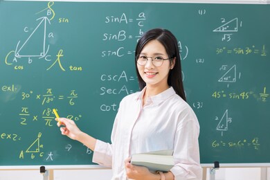 asian senior high school female teacher is teaching online through webcam in classroom