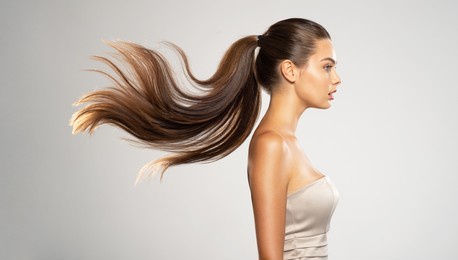 profile portrait of a beautiful woman with a long  hair. young  brunette model with  beautiful hair - isolated on white background. young girl with straight hair flying in the wind.  
