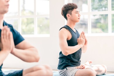 group of asian and caucasian, male and female yoga together in indoor white studio with natural light. concept of diversity, multi ethnic group of people and healthy lifestyle