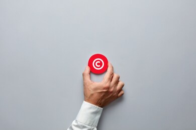 businessman hand holding a red badge with copyright symbol. property rights and brand patent protection in business concept.