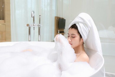 happy asian woman bathes with white foam in a bathtub fun emotions.