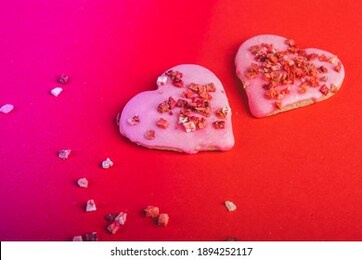 two pair of cookies red heart shaped for valentine's day, toned in trendy neon background. top view. space for text. treats
