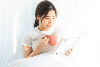portrait of a young asian girl reading a book and drinking coffee
