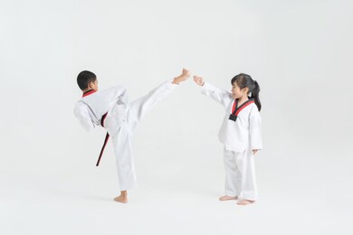 asian children practicing taekwondo in white studio 