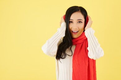 portrait of excited young asian woman wearing ear muffs and warm wool scarf for winter day
