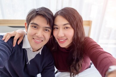 smiling young asian couple on white bed.