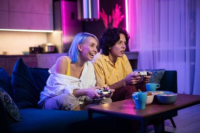 handsome young man teaching how to play the video games to his girlfriend, on the couch, concept about home entertainment, video games.