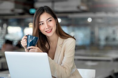asian business women sit in the office and drink coffee look laptop computer 