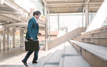 focusing on business man wearing blue formal suit, holding briefcase, hurry and rush running on the steps while going to work in the early morning