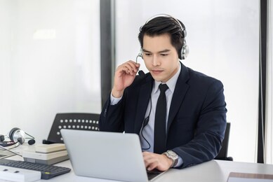 young asian man and a headset delivers a call center in the office with a laptop.