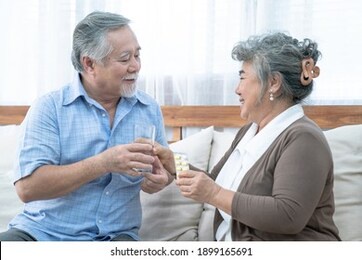 asian elderly couple, taking care of health in retirement, senior woman helping her husband take a pills or vitamin pills at home.