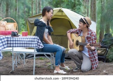 asian traveler's jungle camping trip. couple lover asian tourists pitched tent marquee sing a song play guitar relax natural surroundings for destination of relaxation in holiday get natural therapy.