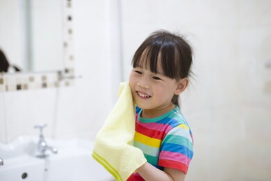 young girl washing face by herself  in bathroom 