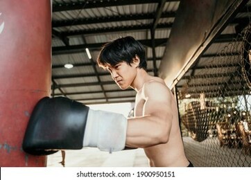 asian man boxer exam exercise hitting punching bag at training camp