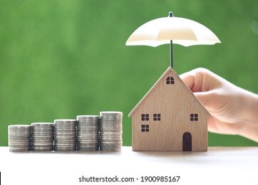 protection, stack of coins money and model house with hand holding the umbrella on natural green background, finance insurance and safe investment concept