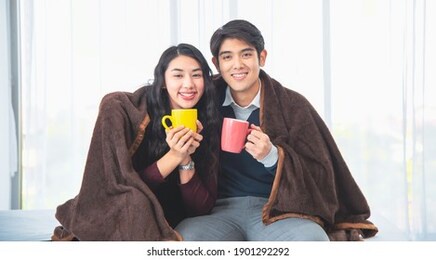 happy young asian couple drinking coffee at home. loving couple with hot drinks. valentine's day