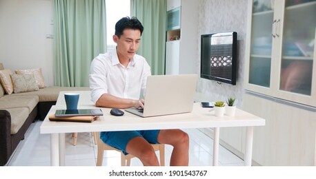 asian man use laptop to work in the living room at home freely