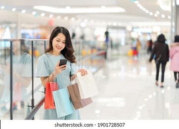 young girl is shopping and using the phone at the mall