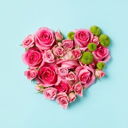 heart shaped bouquet of beautiful fresh pink rose flowers on pastel blue background. minimal valentines day, easter, wedding or mother's day concept. creative spring or summer floral layout. flat lay.