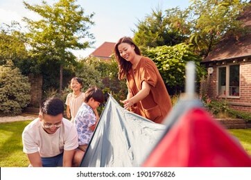 asian family in garden at home putting up tent for camping trip together